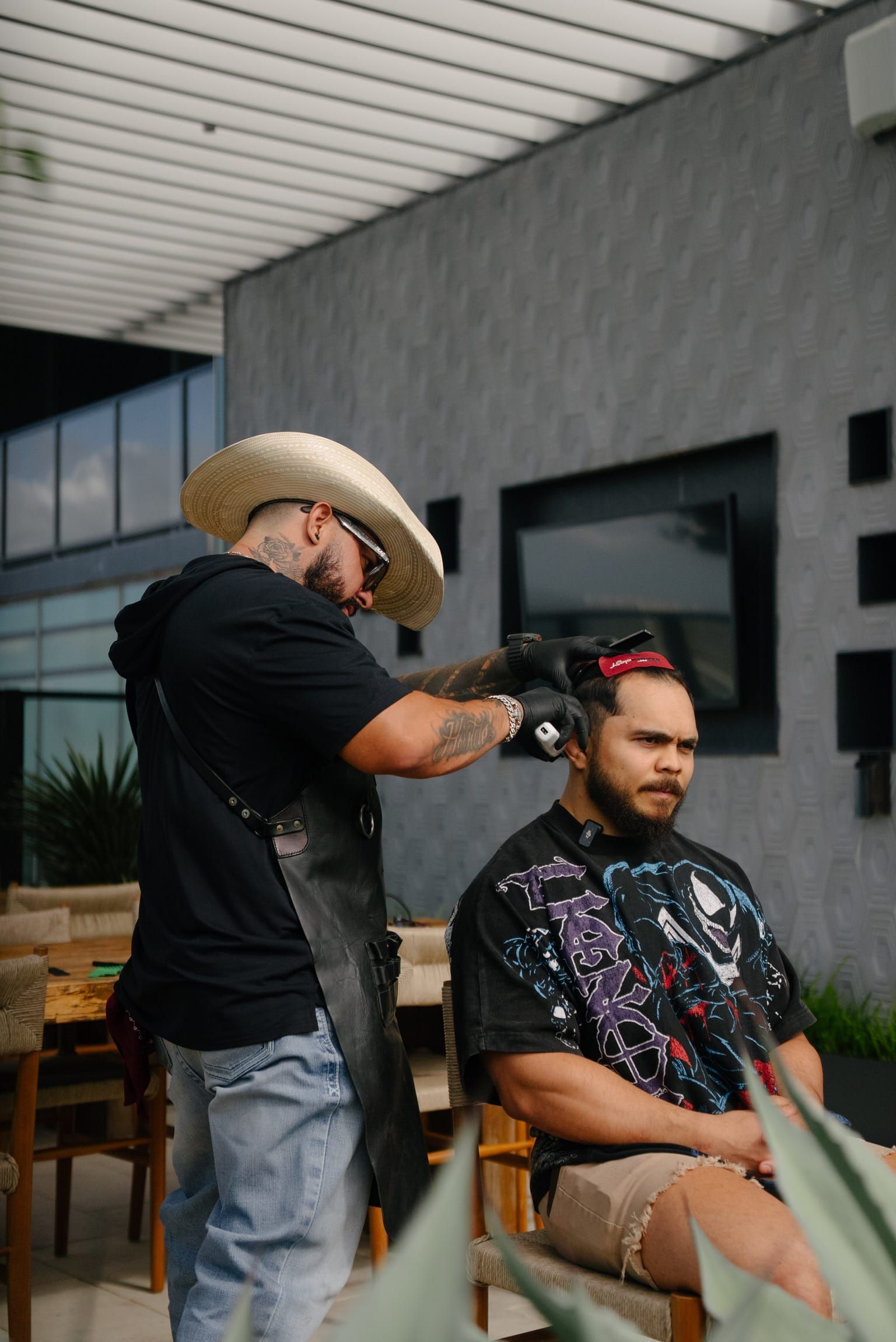 Roy, in black gloves, working through a client's hair with a comb and clippers