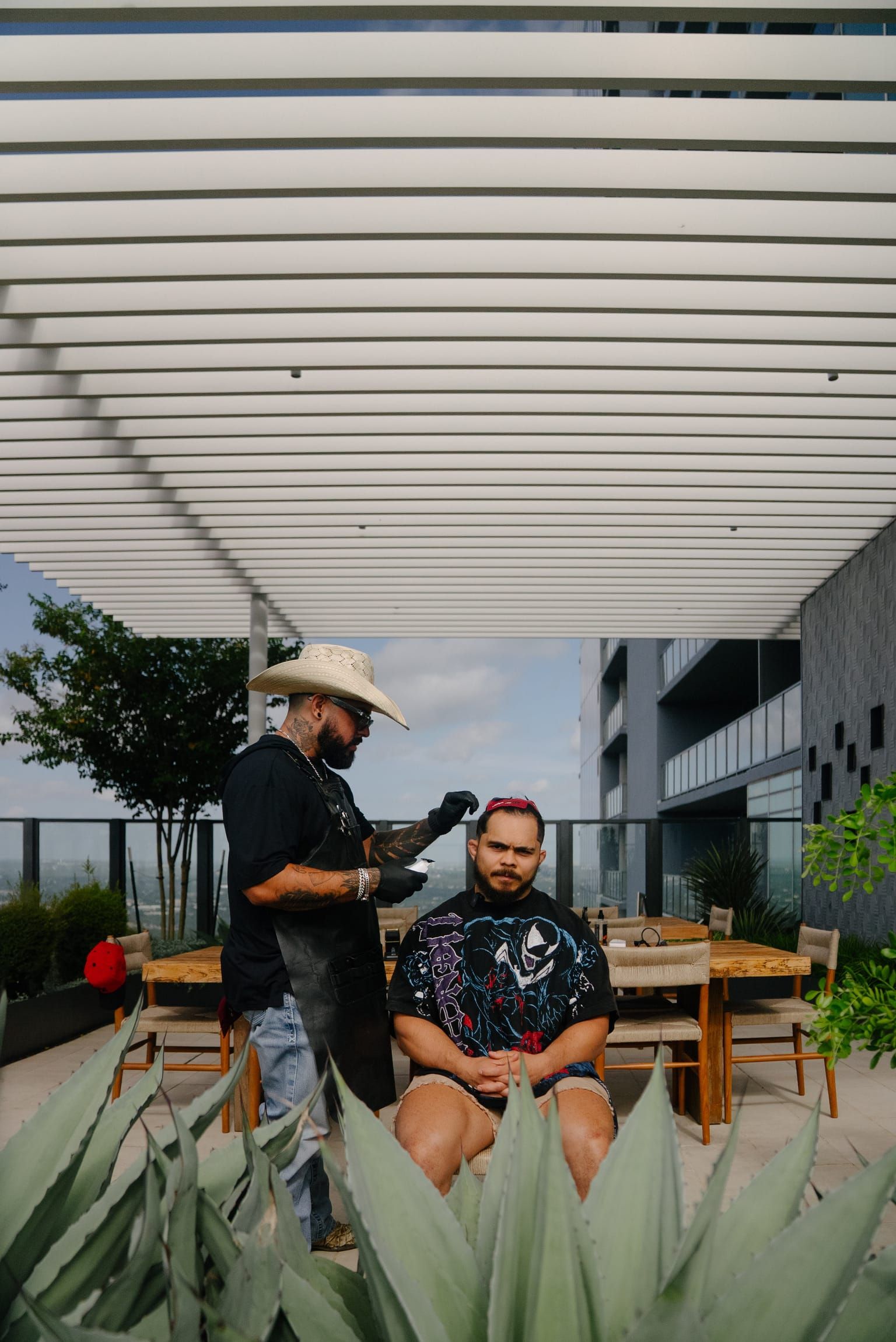 Roy at work under a white pergola, his client seated among agave plants